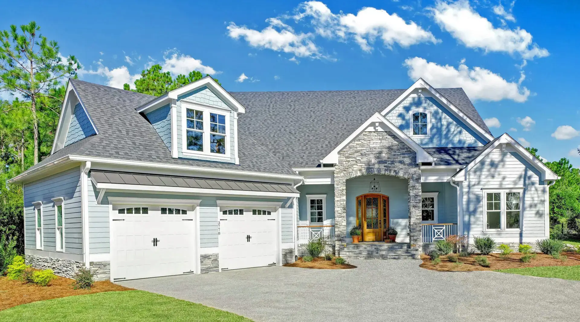 Modern gray house with a three-car garage under a blue sky.